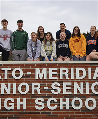  A group of the top ten students posing in front of the school main sign 
